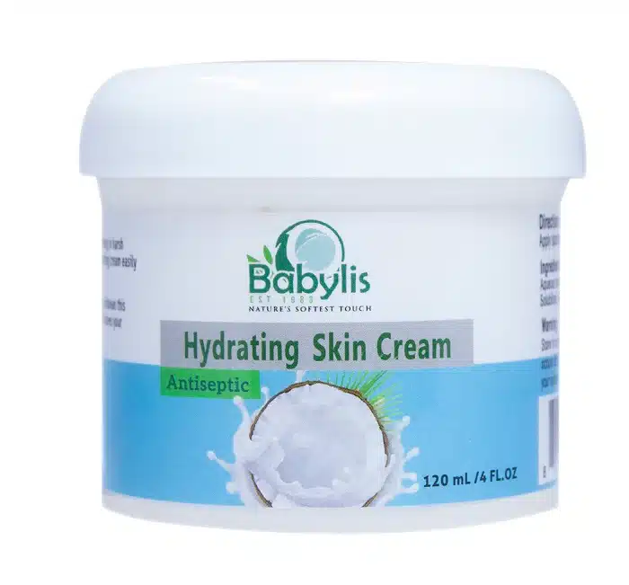 A white plastic tub of Babylis Hydrating Skin Cream with a smooth white lid. The front label features the Babylis logo, which states "EST 1983" and "NATURE'S SOFTEST TOUCH." The words "Hydrating Skin Cream" are printed inside a grey rectangular banner, with a green badge below it that reads "Antiseptic." The bottom portion of the label has a light blue background featuring an illustration of a coconut half splashing into milk or cream, alongside the volume marking "120 mL / 4 FL.OZ