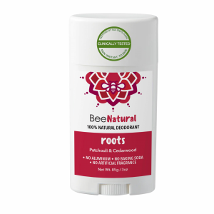 A deodorant stick from the brand "BeeNatural." The deodorant is called "roots" and is labeled as "100% NATURAL DEODORANT." The product features a red label with text listing the scents "Patchouli & Cedarwood" and states "NO ALUMINUM • NO BAKING SODA • NO ARTIFICIAL FRAGRANCE." The label also says "Non-Irritant To Skin," "Clinically Tested," and "Certified By SGS IDEAS Clinic." The weight is listed as "Net Wt. 85g / 3oz." The packaging is a white twist-up style stick with a white cap.